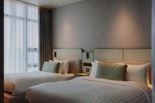 a hotel room with two beds and a window at Sol Beach Namhae in Namhae