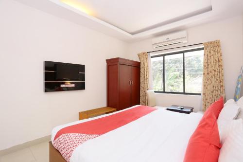 a bedroom with a bed and a tv and a window at Super Townhouse Dona Castle in Kollam