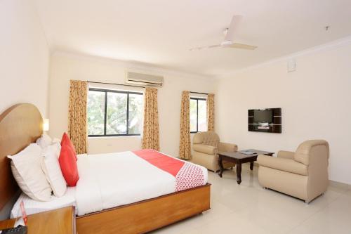 a bedroom with a bed and a desk and chairs at Super Townhouse Dona Castle in Kollam
