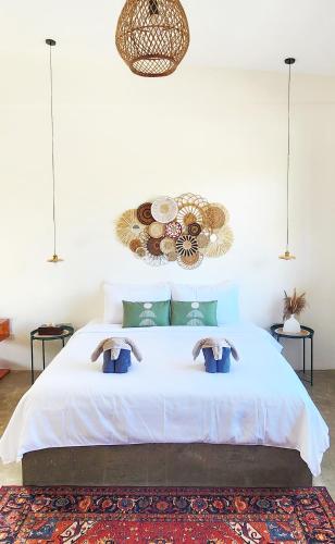 a bedroom with a large white bed with two pillows at Villa Pura Vida Apartments Siargao in General Luna