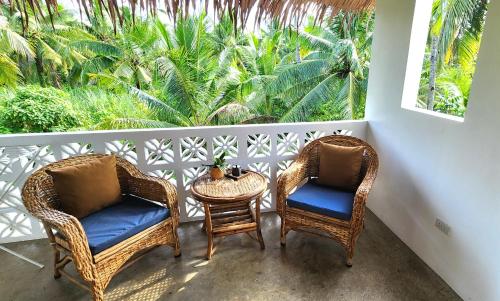 a balcony with two chairs and a table and a window at Villa Pura Vida Apartments Siargao in General Luna