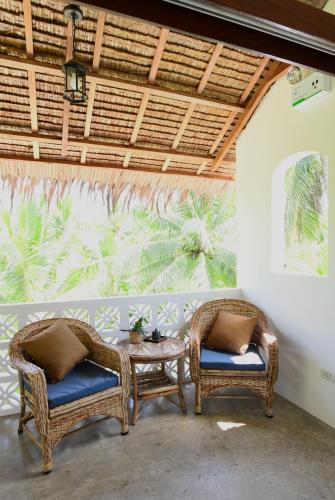 two wicker chairs and a table in front of a window at Villa Pura Vida Apartments Siargao in General Luna