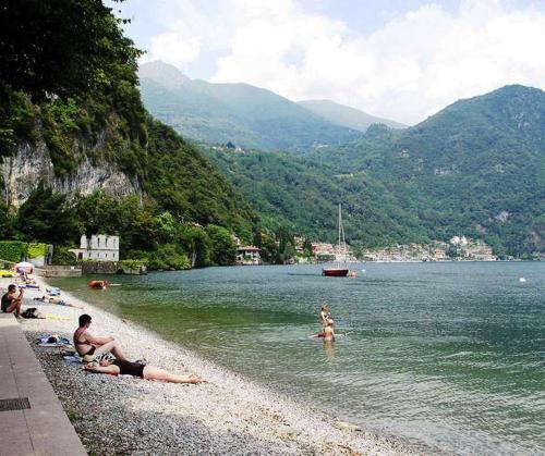 a group of people laying in the water on a beach at La Piazzetta in Menaggio
