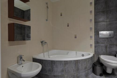 a bathroom with a tub and a toilet and a sink at John's Luxury Apartment in Paralia Katerinis