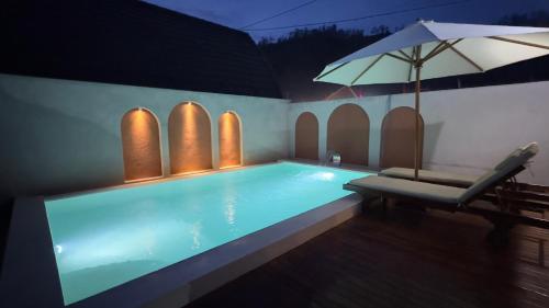 a swimming pool with a chair and an umbrella at Volcano Valley in Kintamani