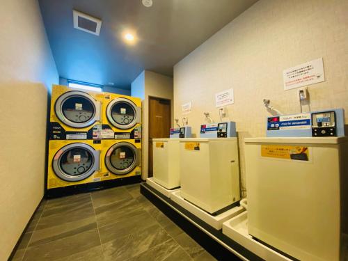 a laundry room with three washing machines in a store at Hotel Route-Inn Ichihara in Ichihara