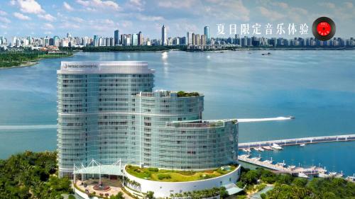 a tall building on the water next to a large city at InterContinental Haikou Seaview by IHG in Haikou