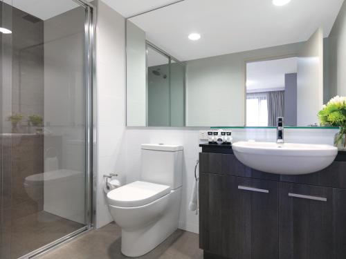 a bathroom with a toilet and a sink and a mirror at Adina Apartment Hotel Sydney Airport in Sydney