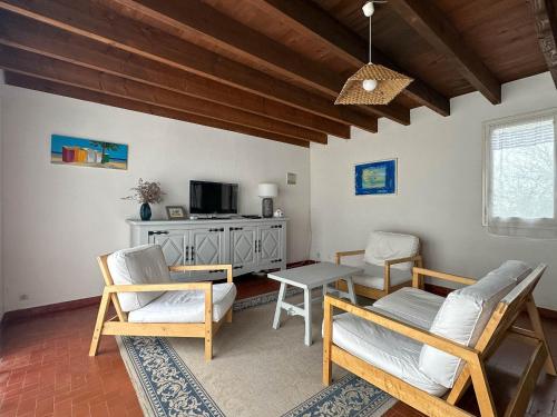 - un salon avec des chaises, une table et une télévision dans l'établissement Maison spacieuse près de la mer avec parking, 10 pers - FR-1-705-106, aux Mathes
