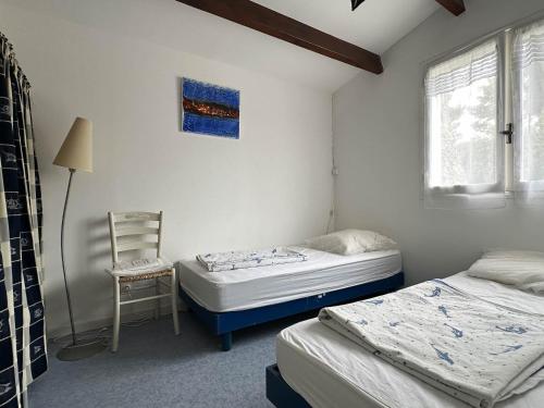 - une chambre avec 2 lits et une chaise dans l'établissement Maison spacieuse près de la mer avec parking, 10 pers - FR-1-705-106, aux Mathes