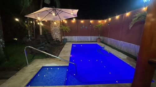 a blue swimming pool at night with an umbrella at Alma y Paz Beach House in Bejuco