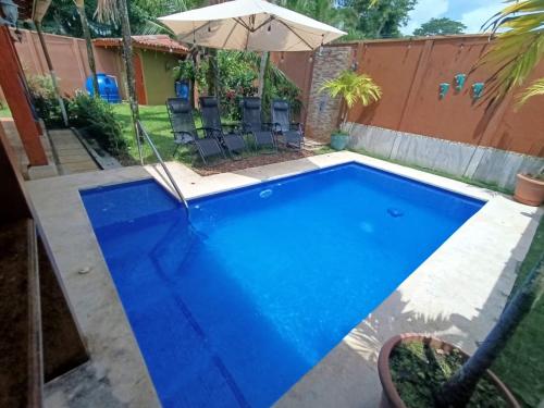 a blue pool with chairs and an umbrella at Alma y Paz Beach House in Bejuco
