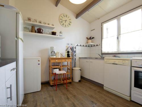 une cuisine avec des appareils blancs et une horloge murale dans l'établissement Villa bord de mer 4 pièces, proche plage, animaux admis - FR-1-705-97, aux Mathes