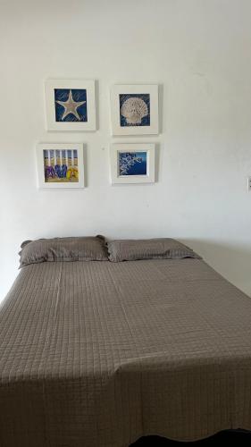 a bedroom with a bed with four pictures on the wall at Casa Sol Canoa Quebrada in Canoa Quebrada