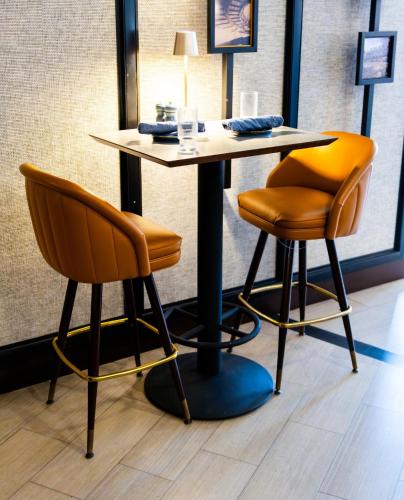a table and two orange chairs in a room at Crowne Plaza Cleveland at Playhouse Square by IHG in Cleveland