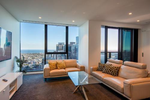 メルボルンにあるUrban Escape - Breathtaking Bay and City View Apartmet with Balconyのソファとテーブルと窓のあるリビングルーム