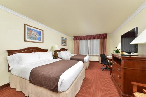 a hotel room with two beds and a desk and a television at Holiday Inn Rancho Cordova - Northeast Sacramento by IHG in Rancho Cordova