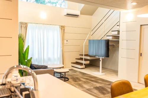 un soggiorno con TV a schermo piatto e divano di CORAL ISLAND 1棟貸し 天然ビーチまで徒歩5秒 ジャグジー付きVilla a Nago