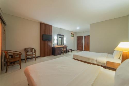 a hotel room with two beds and a desk at Nirmala Hotel Jimbaran in Jimbaran