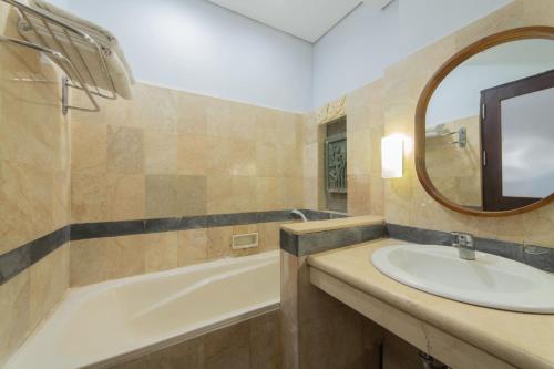 a bathroom with a sink and a tub and a mirror at Nirmala Hotel Jimbaran in Jimbaran