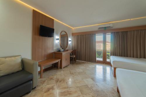 a hotel room with a couch and a mirror at Nirmala Hotel Jimbaran in Jimbaran