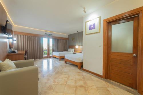a hotel room with two beds and a couch at Nirmala Hotel Jimbaran in Jimbaran