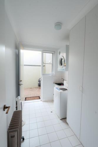 a white kitchen with a sink and a refrigerator at Whalers Rest Ocean front Whale watching in Encounter Bay