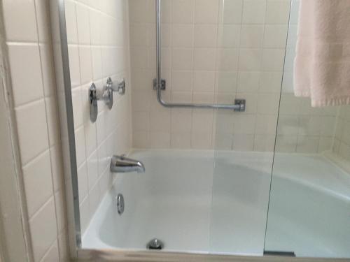 a bathroom with a tub with a glass shower door at Hotel Amari in San Francisco