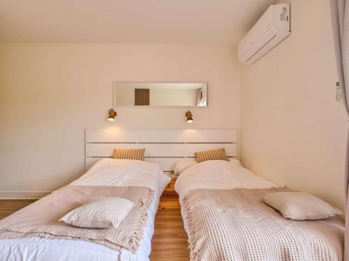 2 letti in una camera con pareti bianche e pavimenti in legno di Studio rénové et climatisé avec balcon pour 2 personnes - FR-1-841-24 a Barbotan-les-Thermes