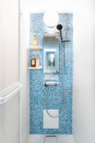 a bathroom with a shower with blue tiles at Nihonbashi Kakigara Ryokan in Tokyo