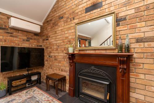 a brick fireplace with a mirror on top of it at 3BR Home near Canberra Hospital and Parliament - Hosted by CanStay in Harman