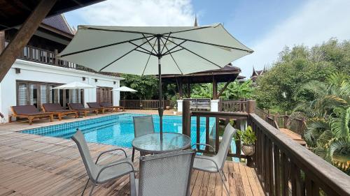 a patio with a table and chairs and an umbrella at CM14 Beds & Private Pool in Mae Pim