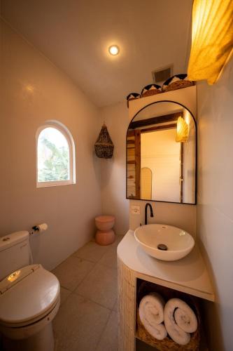a bathroom with a toilet and a sink and a mirror at Casa Coco in Nusa Lembongan