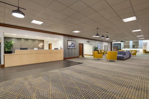 an office lobby with a waiting area and yellow chairs at Holiday Inn Louisville East - Hurstbourne by IHG in Louisville