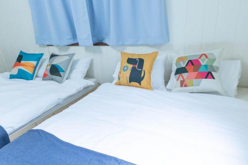 two beds with colorful pillows sitting next to each other at エイトハウス辻 in Naha
