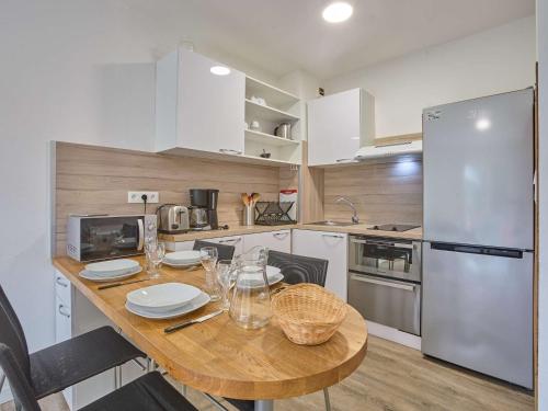 a kitchen with a wooden table and a refrigerator at Spacieux T2 rénové, vue nature, balcon sud, Wifi, parking à Barbotan - FR-1-841-54 in Barbotan-les-Thermes