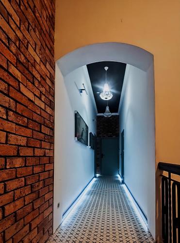 a hallway with a brick wall and a chandelier at Rynek Experience - Apartamenty in Gliwice