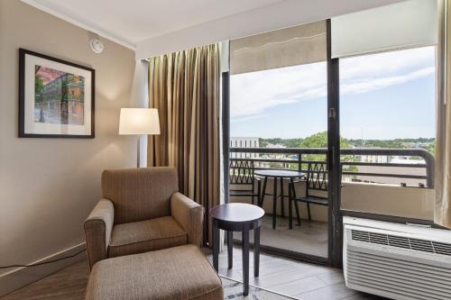 a hotel room with a chair and a balcony at Crowne Plaza Executive Center Baton Rouge by IHG in Baton Rouge