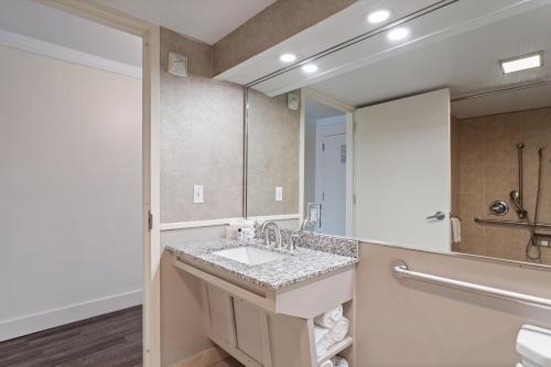 a bathroom with a sink and a large mirror at Crowne Plaza Executive Center Baton Rouge by IHG in Baton Rouge