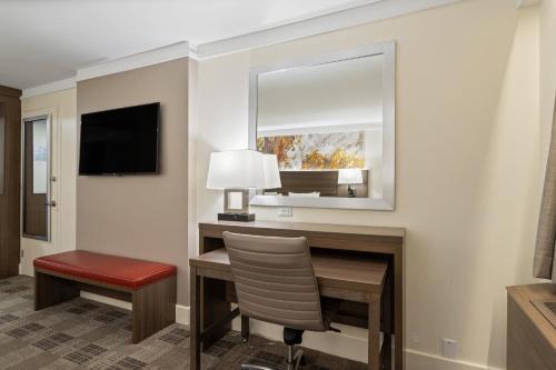 a room with a desk with a chair and a mirror at Crowne Plaza Executive Center Baton Rouge by IHG in Baton Rouge