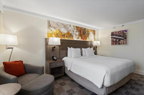 a hotel room with a bed and a chair at Crowne Plaza Executive Center Baton Rouge by IHG in Baton Rouge