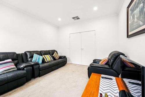 a living room with a black leather couch and a table at Everything You Need - Family Retreat in Clyde in Clyde