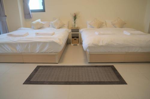two twin beds in a room with a rug at Yuejin Port B&B in T'u-k'u