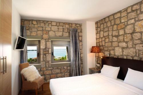 a bedroom with a bed and a stone wall at Executive Rhodes Villa Villa Althea 2 Bedroom Villa With Sea Views Pefkos in Pefki Rhodes