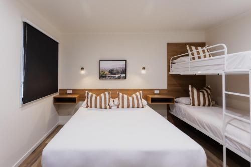 a bedroom with two bunk beds and a flat screen tv at Coomera Lodge Hotel in Gold Coast