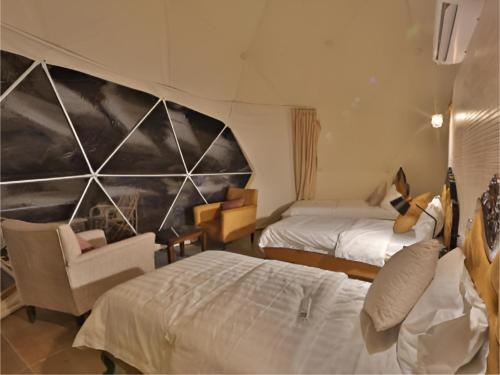 a hotel room with two beds and a chair at Rum rose luxury camp in Wadi Rum