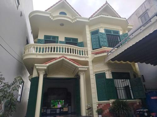 Una casa grande con puertas verdes y balcón. en MoonNest vila catba, en Cat Ba
