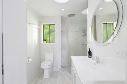 a white bathroom with a toilet and a mirror at Noosa River Retreat Holiday Apartments in Noosaville