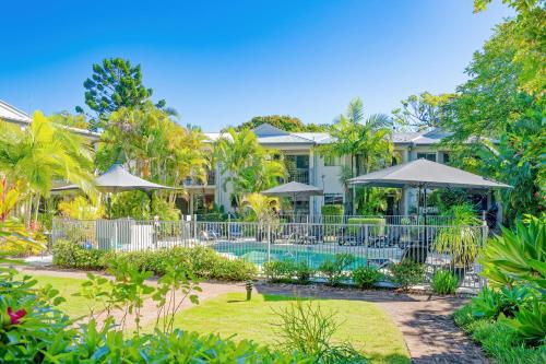 a house with a swimming pool and trees at Noosa River Retreat Holiday Apartments in Noosaville