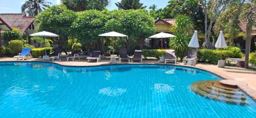 a large blue swimming pool with chairs and umbrellas at Lanta Cozy House 02 in Ko Lanta